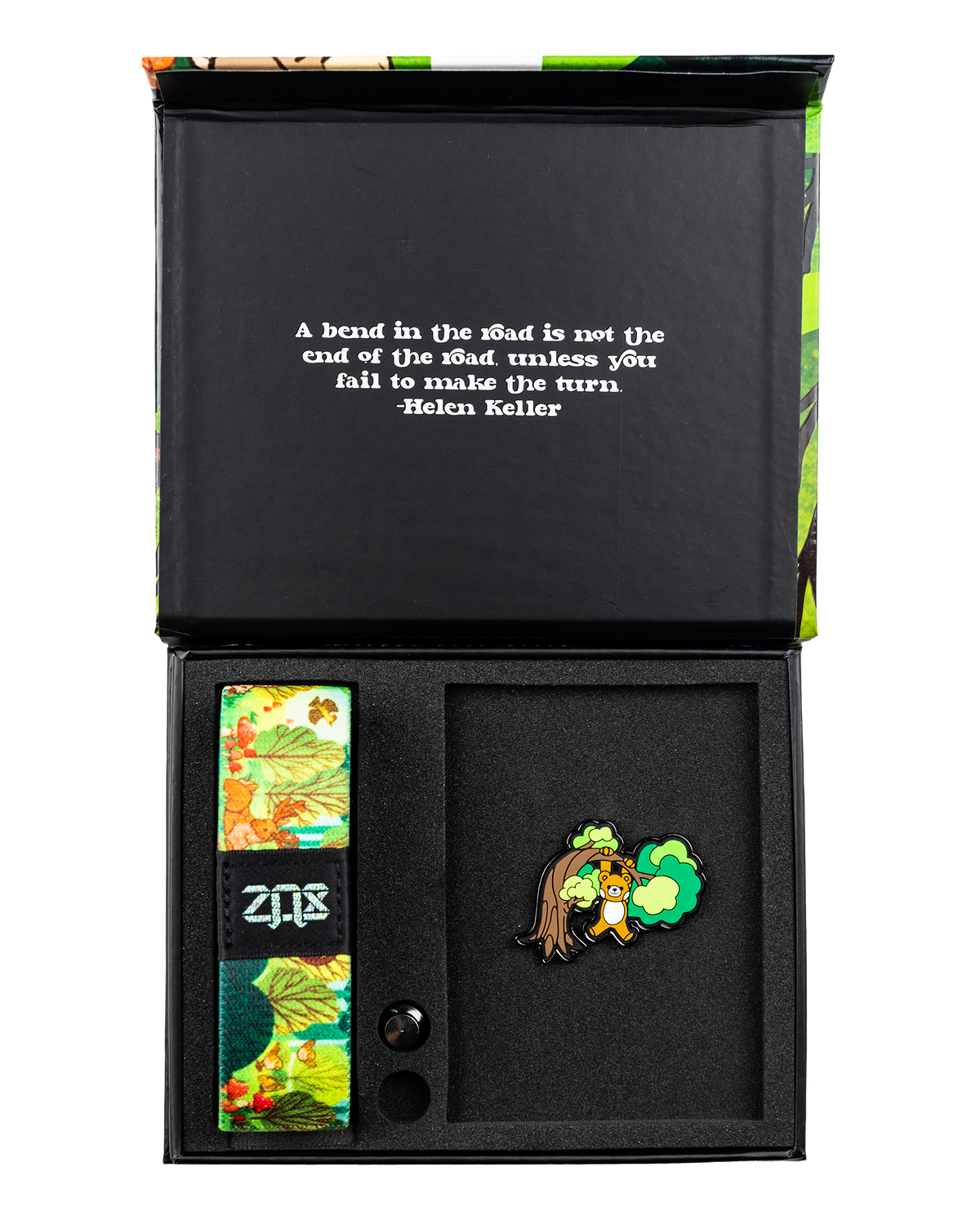 This is a reversible strap. The outside design is a cartoon scene of a bear climbing a tree in the jungle. It comes with a matching lapel pin of the bear hanging on a limb, and a collector's box. 