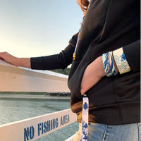 Lifestyle photo of girl holding a The Great Wave lanyard with the straps on her wrist showing the inside and outside of The Great Wave
