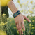 Lifestyle image of Be Kind on wrist among mustard flowers
