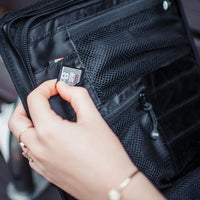 A woman removing an SD card from an opened camera bag which shows multiple little pockets for extra gear