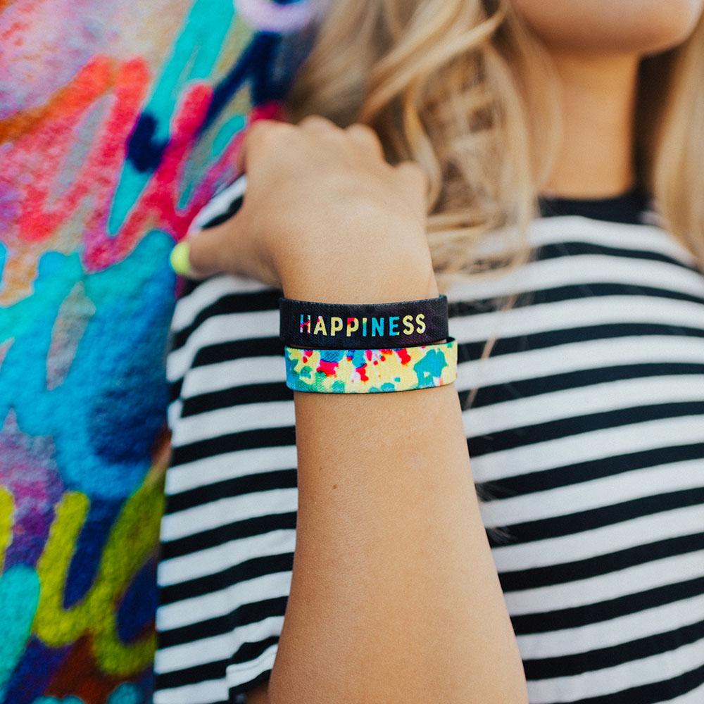 Lifestyle photo up close of a girl's wrist showing the inside and outside design of the happiness single