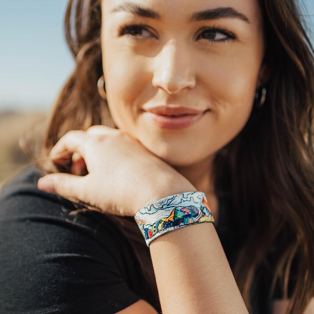 Lifestyle image of Happy To Be Here on wrist of smiling model