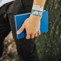 Lifestyle close up of someone holding a book in hand and 2 Innovate on their wrist