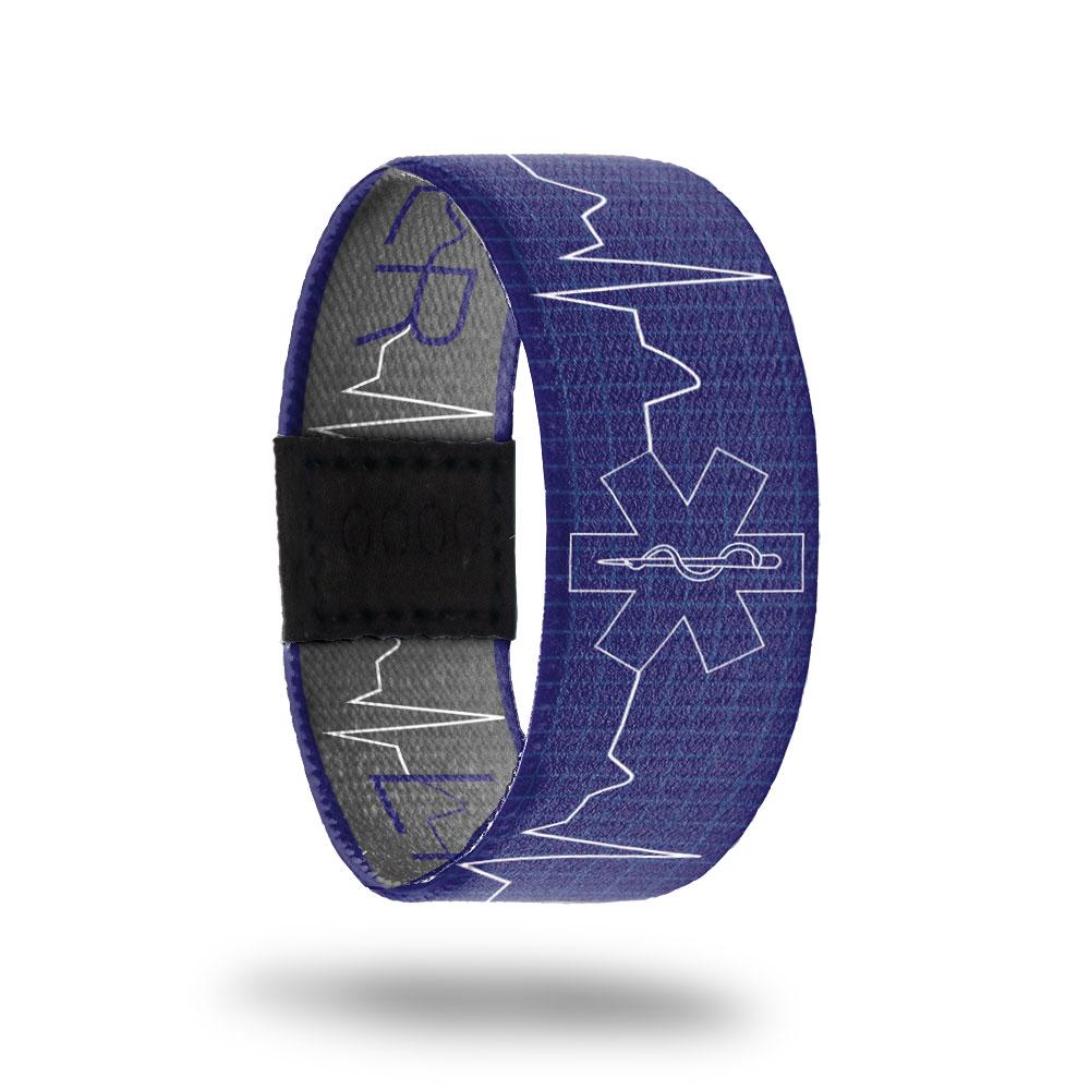 Outside design of Life Saver. Dark blue background with white lines as a grid pattern. One line that runs the length of the design which mimics the lines of a heart monitor and at the center is the paramedic logo in thin white lines