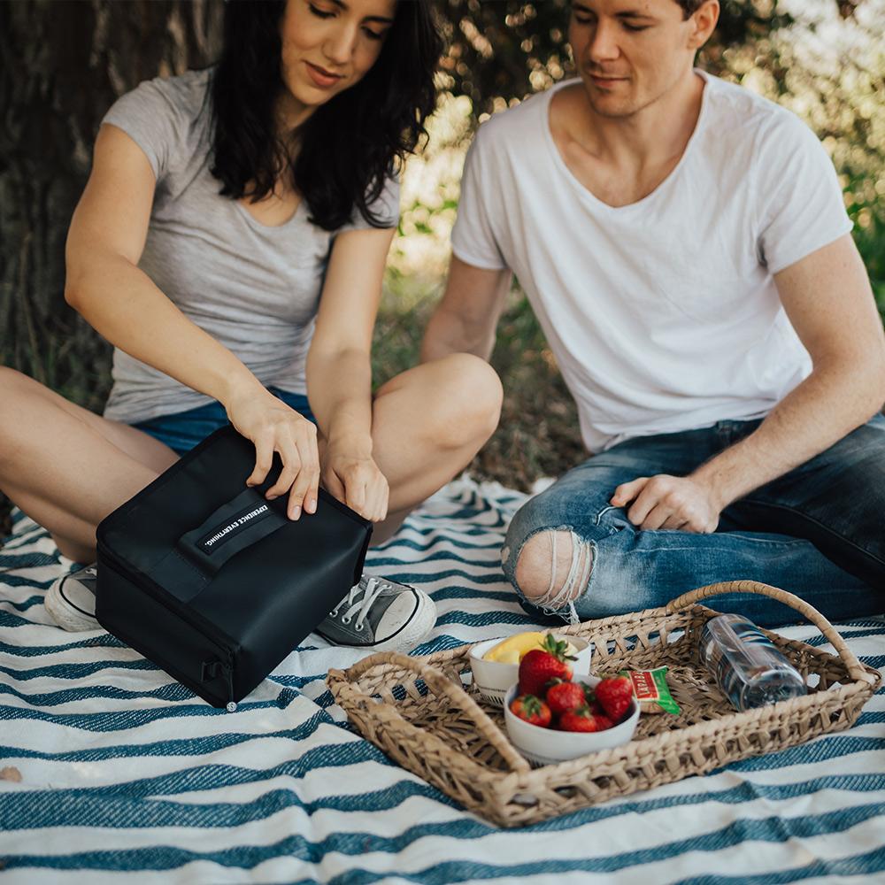 couple on a blanket opening the lunch box to remove food from it