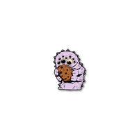 Enamel pin photo for 2020 - Day 7 - Nikki Nine-Eyes: light purple monster with 9 eyes, 4 arms, and spikes on back holding a cookie