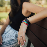 Lifestyle photo up close of a girl's wrist resting on a bench showing the inside and outside design of the peace single