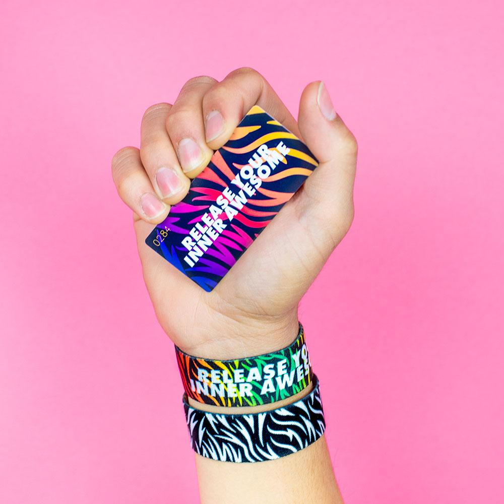 Studio Image of hand holding card that says Release Your Inner Awesome with 2 Release Your Inner Awesome straps on their wrist