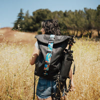 Lifestyle photo of someone hiking with a backpack on while the roll capsule is connected to the side of it
