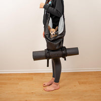A woman with a dog carrier with the roll connected to the bottom that is holding a yoga matt