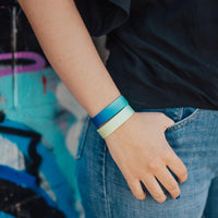 lifestyle photo of girl wearing begin again with dark blue to light blue gradient above light green to yellow gradient wristband