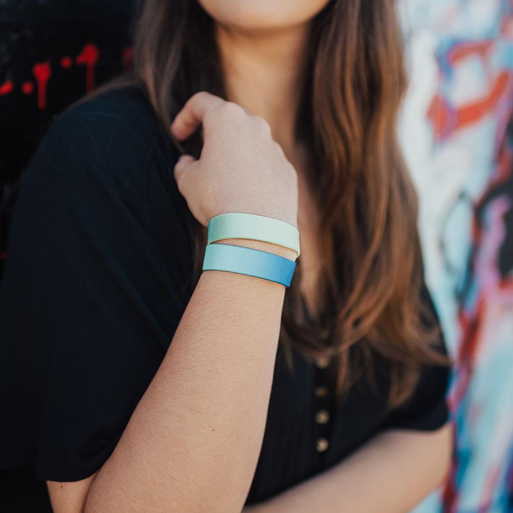 lifestyle photo of girl wearing begin again with dark blue to light blue gradient below light green to yellow gradient wristband