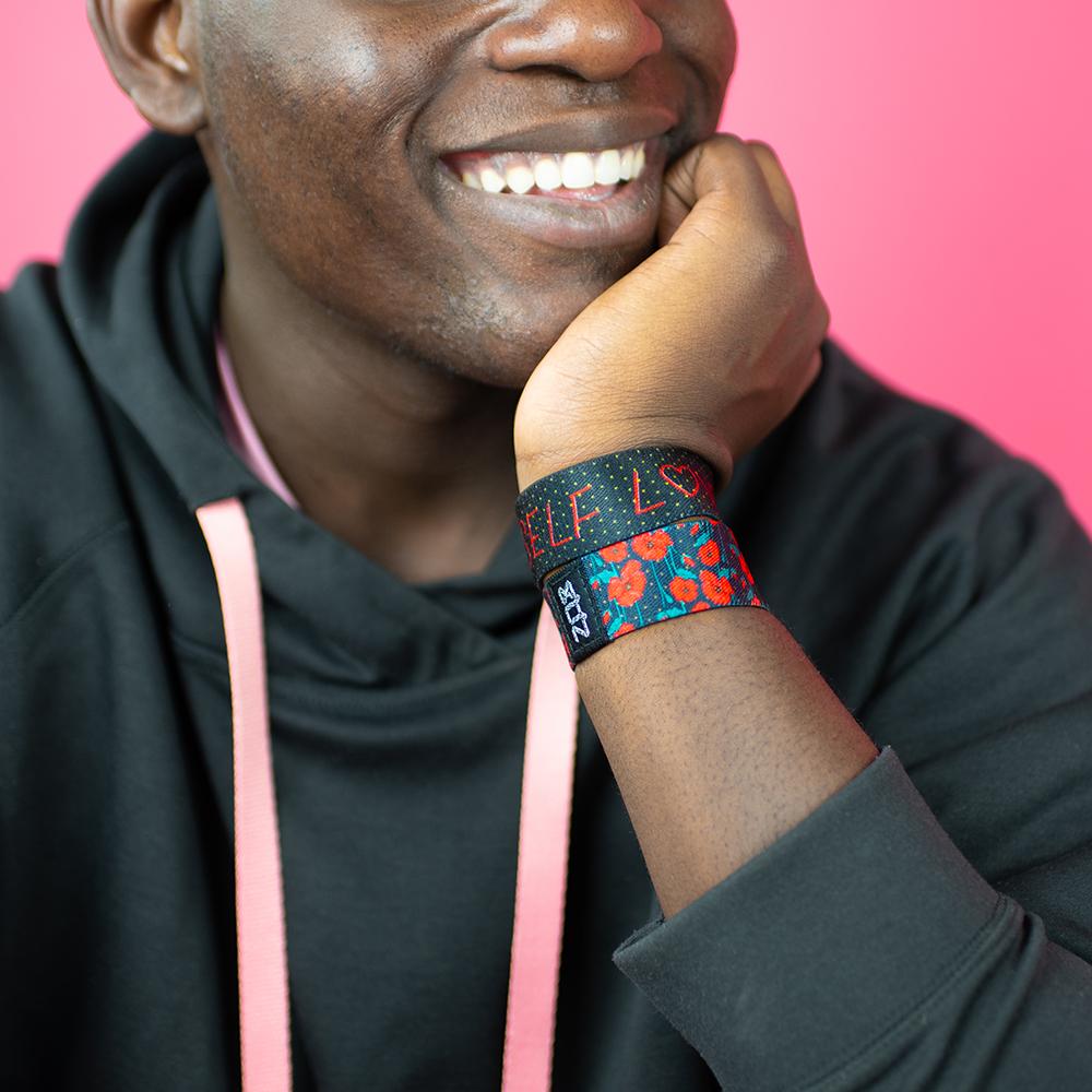 Studio close up image of smiling model and a Self Love on their wrist