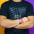 Studio image of model wearing a Zox logo shirt and arms crossed with 2 Stay Strong on wrist