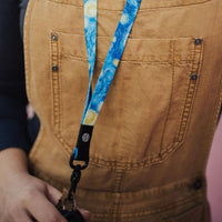 Lifestyle close up image of someone wearing the Starry Night lanyard and holding it by the clip