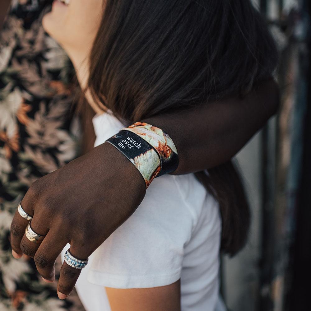 Lifestyle image of someone's arm around someone's shoulder wearing 2 Watch Over Me